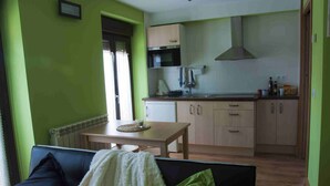 Un espace de vie compact comprenant un coin cuisine, un coin repas et un espace détente avec un canapé et une table.