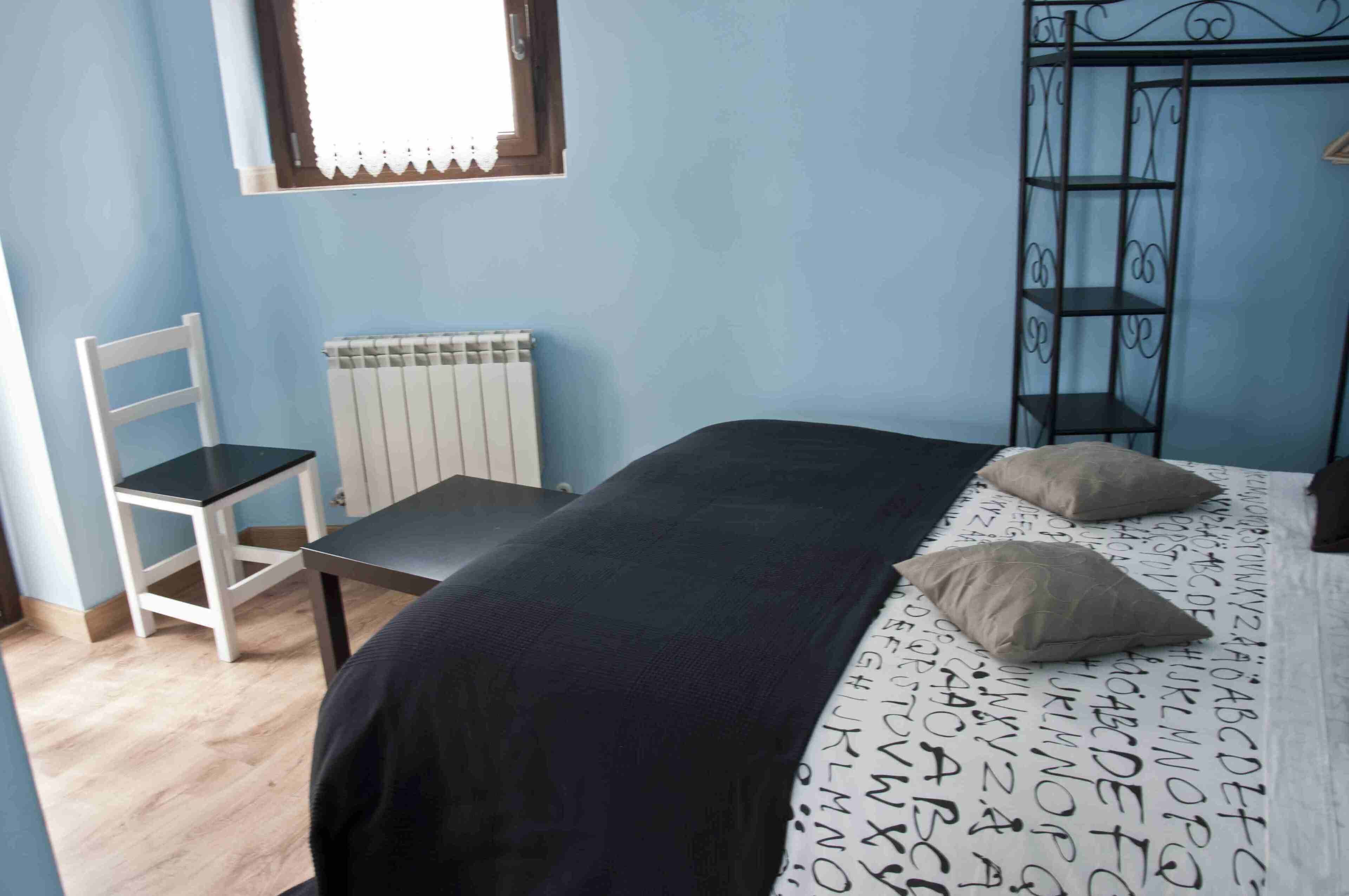 Une chambre à coucher avec un lit, une chaise, un radiateur et une fenêtre.