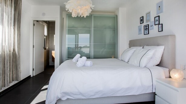 A modern hotel room with a large bed, a bedside table, a decorative light fixture, and a view through a glass door. - VALLESA - Modern villa with private pool near the beach and supermarkets (Calpe)