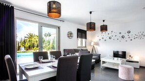 A modern living room with a dining area, a TV, and a pool view. - VALLESA - Modern villa with private pool near the beach and supermarkets (Calpe)