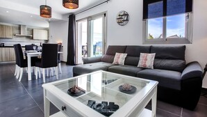 A modern living room with a glass coffee table, grey sofa, and black chairs. - VALLESA - Modern villa with private pool near the beach and supermarkets (Calpe)