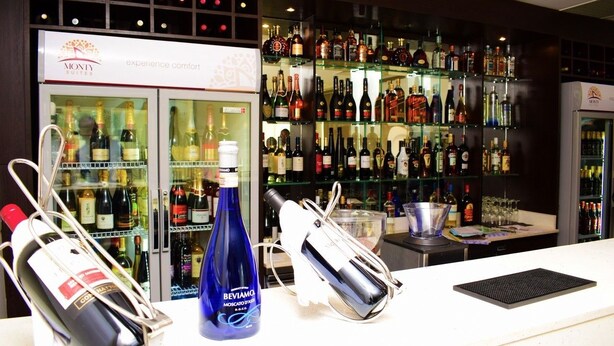Un coin bar équipé d’une cave à vin, d’une bouteille de Beviama Moscato et d’un shaker à cocktails.