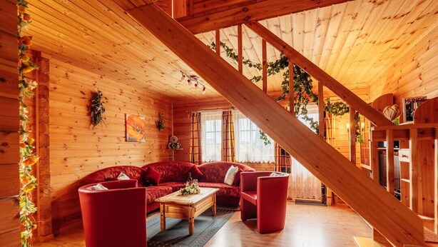 Un intérieur chaleureux avec des éléments en bois, notamment un canapé rouge, une table basse en bois et un escalier.