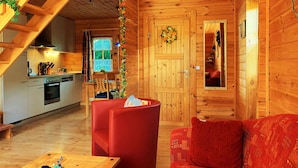L’intérieur d’un chalet en bois chaleureux et accueillant, avec une cuisine, un canapé rouge et un escalier.