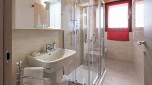 Un baño moderno con cabina de ducha de vidrio, un lavabo con espejo y un inodoro.