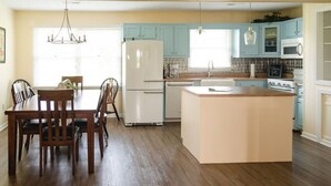 A spacious kitchen with a central island, light blue cabinets, and a dining area with wooden chairs.