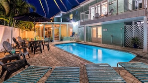 A two-story house with a swimming pool, outdoor furniture, and a patio area.
