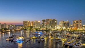 A marina with multiple boats docked, surrounded by high-rise buildings with illuminated windows.