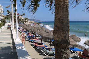 A beach with sun loungers, umbrellas, and a palm tree. - Beach 75 meter - sea view - centre - Wifi - international tv channels - 4 pers. (Nerja)