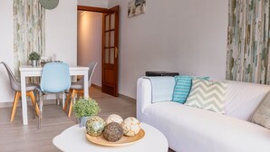 Una sala de estar moderna con un sofá blanco, una mesa de comedor con sillas y bolas decorativas sobre una mesa de centro.