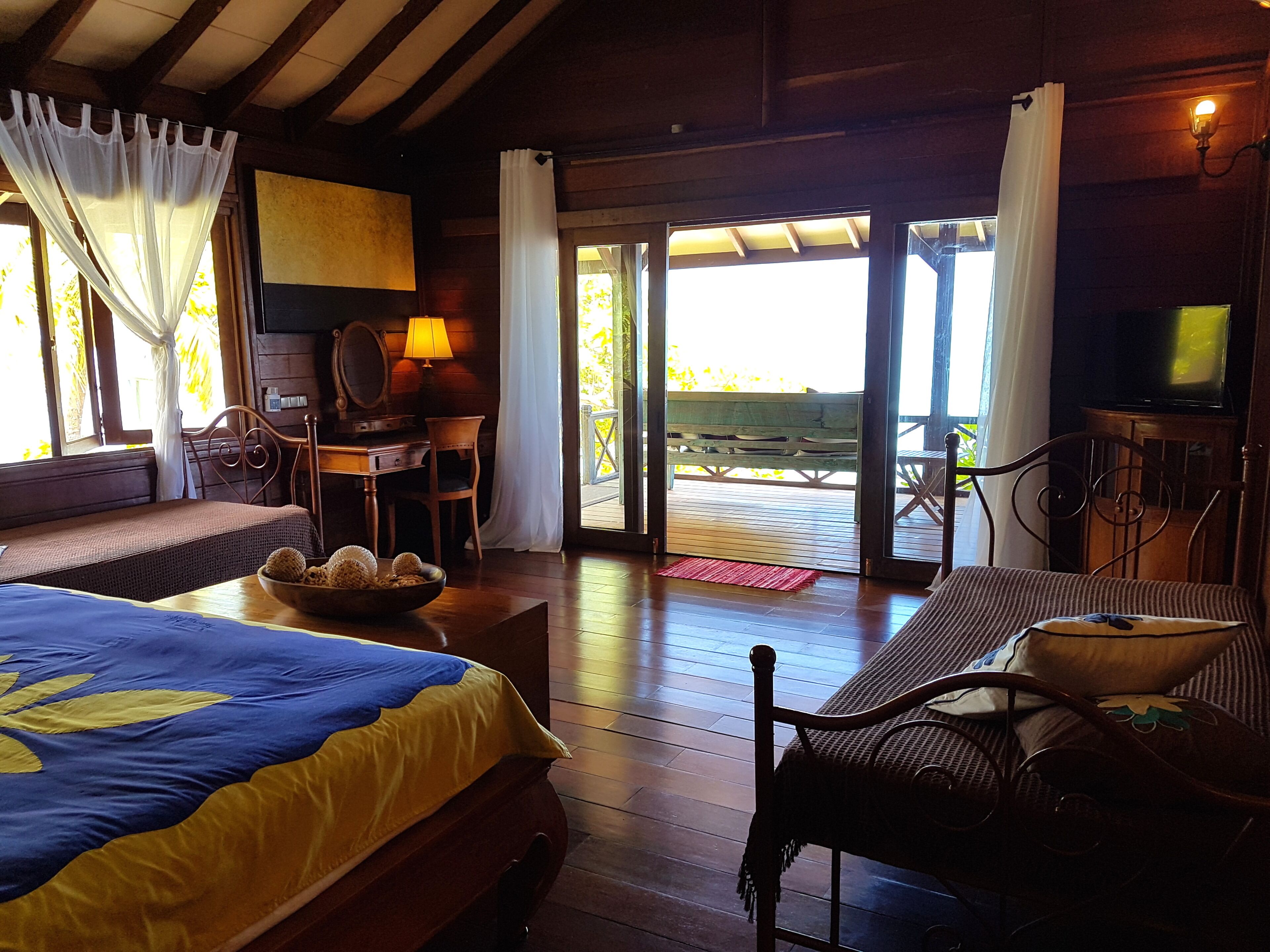 Una habitación con una cama, un escritorio, una silla, un televisor y vistas por la puerta.