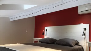 A bedroom with a bed, two bedside tables, a red wall, a white ceiling, and an air conditioning unit. - New Ad - Charming quiet house, air conditioning, shared pool (Châteaurenard)