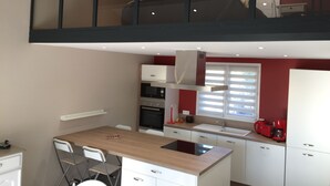 A compact kitchen with a central island, built-in oven, and a window with blinds. - New Ad - Charming quiet house, air conditioning, shared pool (Châteaurenard)