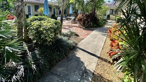 Un camino conduce a un edificio con tejado de baldosas, rodeado de plantas y árboles.