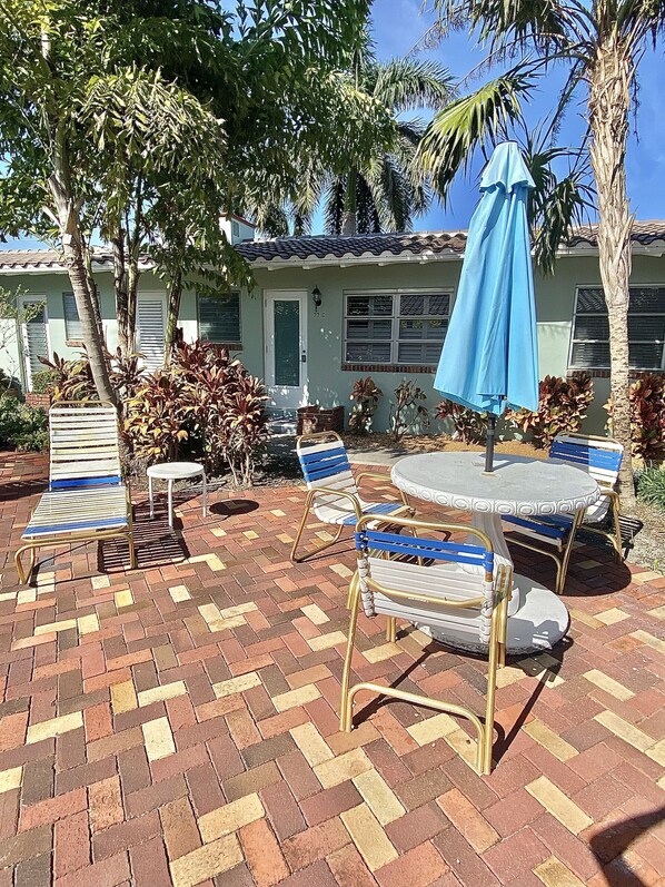 A patio with outdoor furniture, a blue umbrella, and a house with a tiled roof. - 300 STEPS TO THE BEACH (Delray Beach)