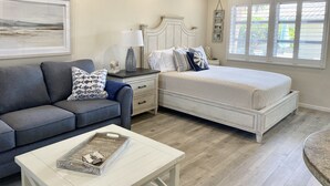 Un dormitorio con cama, mesita de noche, cómoda, sofá y mesa de centro.