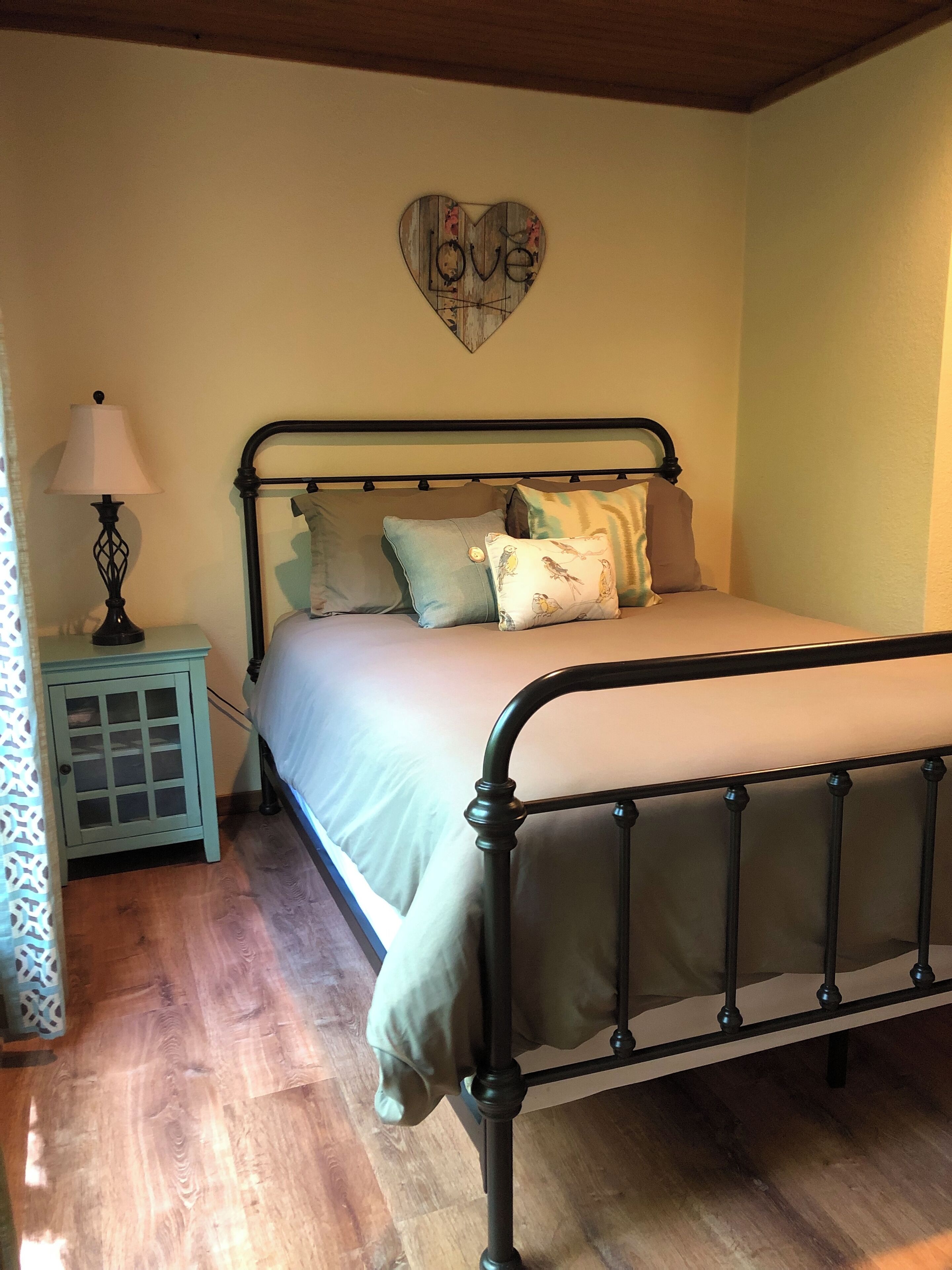 A bedroom with a bed, a nightstand, a lamp, and a wall decoration.