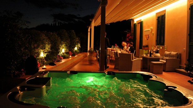 Uma área de hidromassagem com espaço de estar coberto e uma piscina.