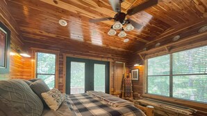 Une chambre confortable dans un chalet, avec un lit, un banc et un ventilateur de plafond.