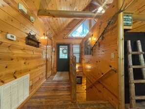 Cozy cabin-style lodging with a rustic atmosphere, featuring a wooden hallway with a skylight and a wooden ladder.