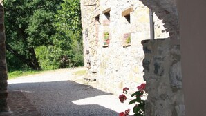 An arched stone doorway leading to a courtyard with a gravel path and a stone building in the background. - Tuscan holiday home near the sea between Siena, Florence and Pisa (Montieri)