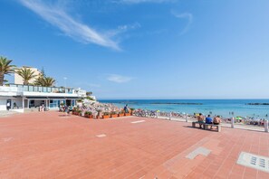 Un paseo marítimo en la playa con un restaurante, zonas de estar y vistas al mar.