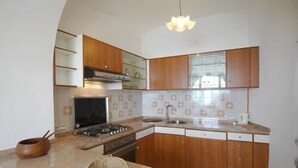 A kitchen with wooden cabinets, a gas stove, a sink, and a window. - RAVELLO "Nonna Anna" AMALFI COAST (RAVELLO)