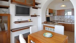 A compact kitchen with wooden cabinets, a built-in TV, and a dining area with a table and chairs. - RAVELLO "Nonna Anna" AMALFI COAST (RAVELLO)