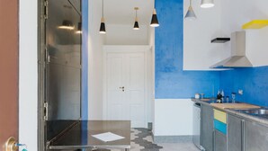 Een moderne keuken met een rvs aanrecht, een witte deur en een blauwe accentmuur.