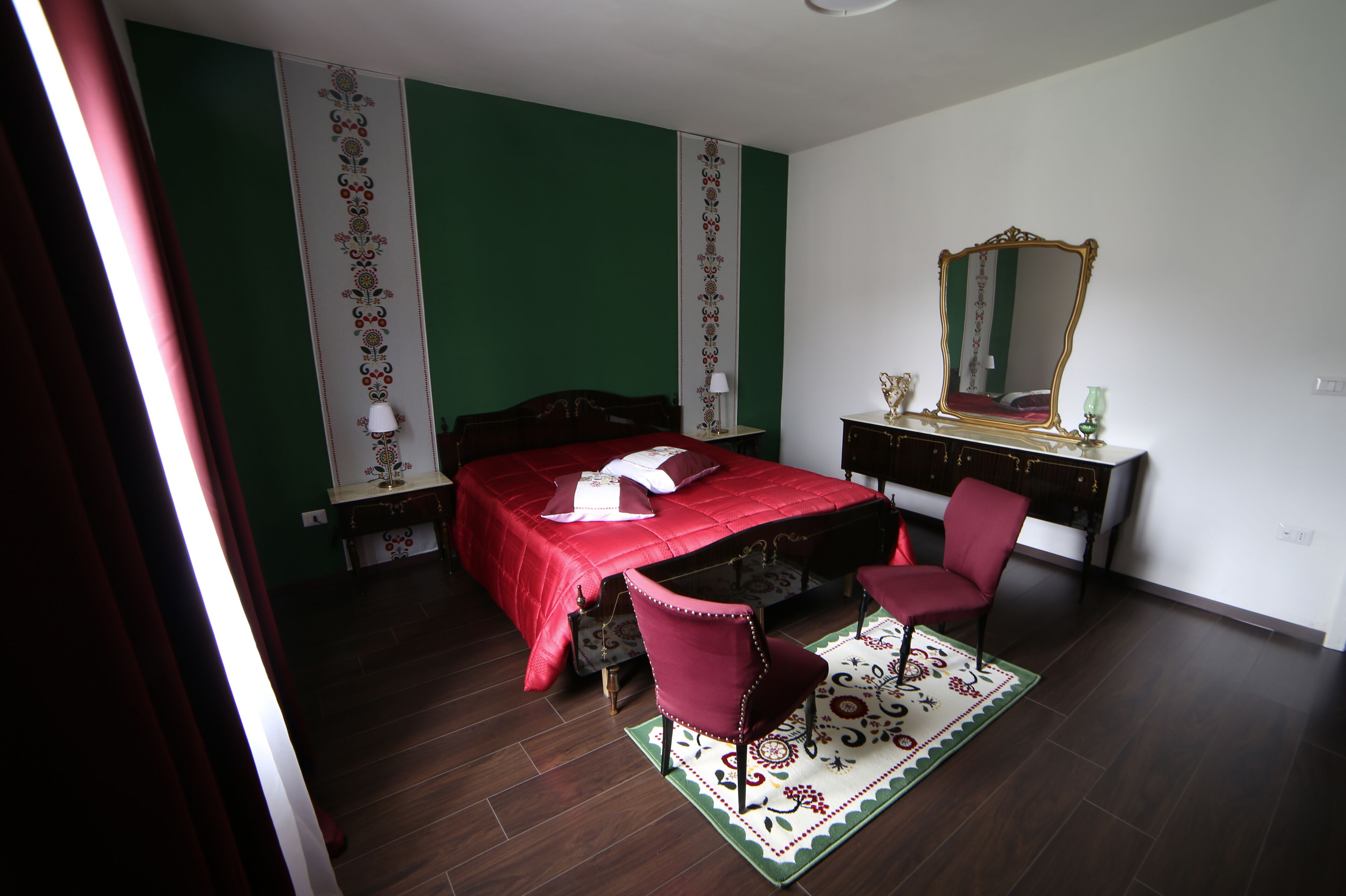 Een slaapkamer met een bed, een stoel, een kapstok en een spiegel.