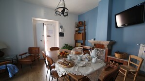 A dining area with a table set for breakfast, chairs, a television mounted on the wall, and a fireplace. - "THE HOUSE OF THE VILLAGE" ....... (Brienza)