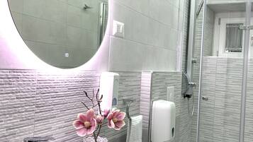 Een moderne badkamer met een grote ronde wastafel, een toilet, een douche en een spiegel.