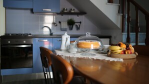 A kitchen with blue cabinets, a stove, and a dining table with a fruit bowl. - "THE HOUSE OF THE VILLAGE" ....... (Brienza)