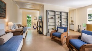 A spacious living room with a sofa, armchairs, and a bookshelf.