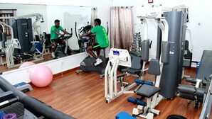 Een sportschool met trainingsapparatuur, een spiegel en een roze fitnessbal.