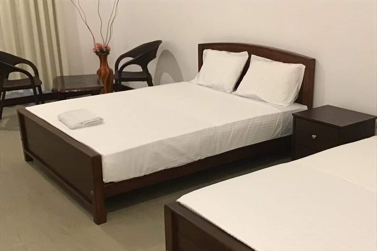 Une chambre d’hôtel avec un lit simple, une table de chevet, une chaise et une petite table.