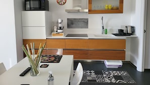 Une cuisine moderne équipée d’un four à micro-ondes, d’une machine à café et d’un évier. On y trouve un meuble en bois et un plan de travail blanc.