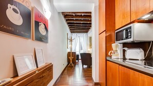 Une cuisine avec des meubles de rangement en bois, un four à micro-ondes et une machine à café. On peut voir des certificats encadrés sur une étagère en bois.
