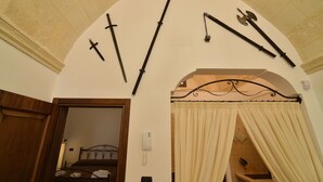 Ein Zimmer mit einem Bett, einer Duschkabine und einer Wand mit angebrachten Waffen.