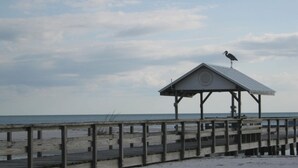 A wooden pier leading to a small, open-sided shelter by the beach.