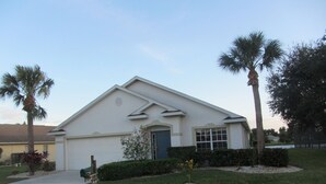 A single-story house with a front garage, a small front yard with a lawn and a few trees, and a mailbox.