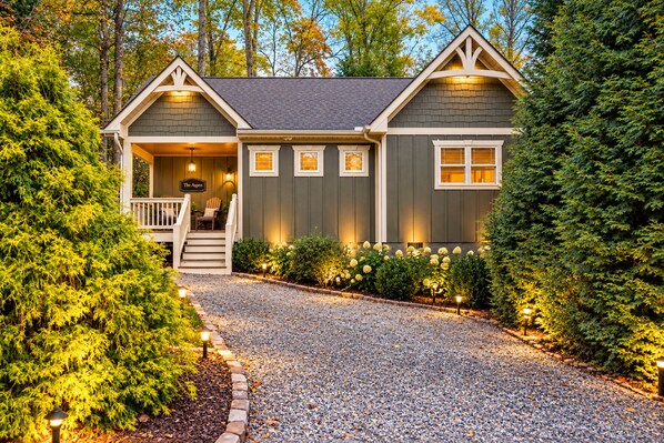 A two-story house with a front porch, a staircase, and a gravel driveway.