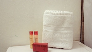A bathroom with a white towel, two bottles of shampoo, and a red box labeled "TAROCCO". - Gladioli 1101 - That's all Puerto Rico (Ponce Pueblo)