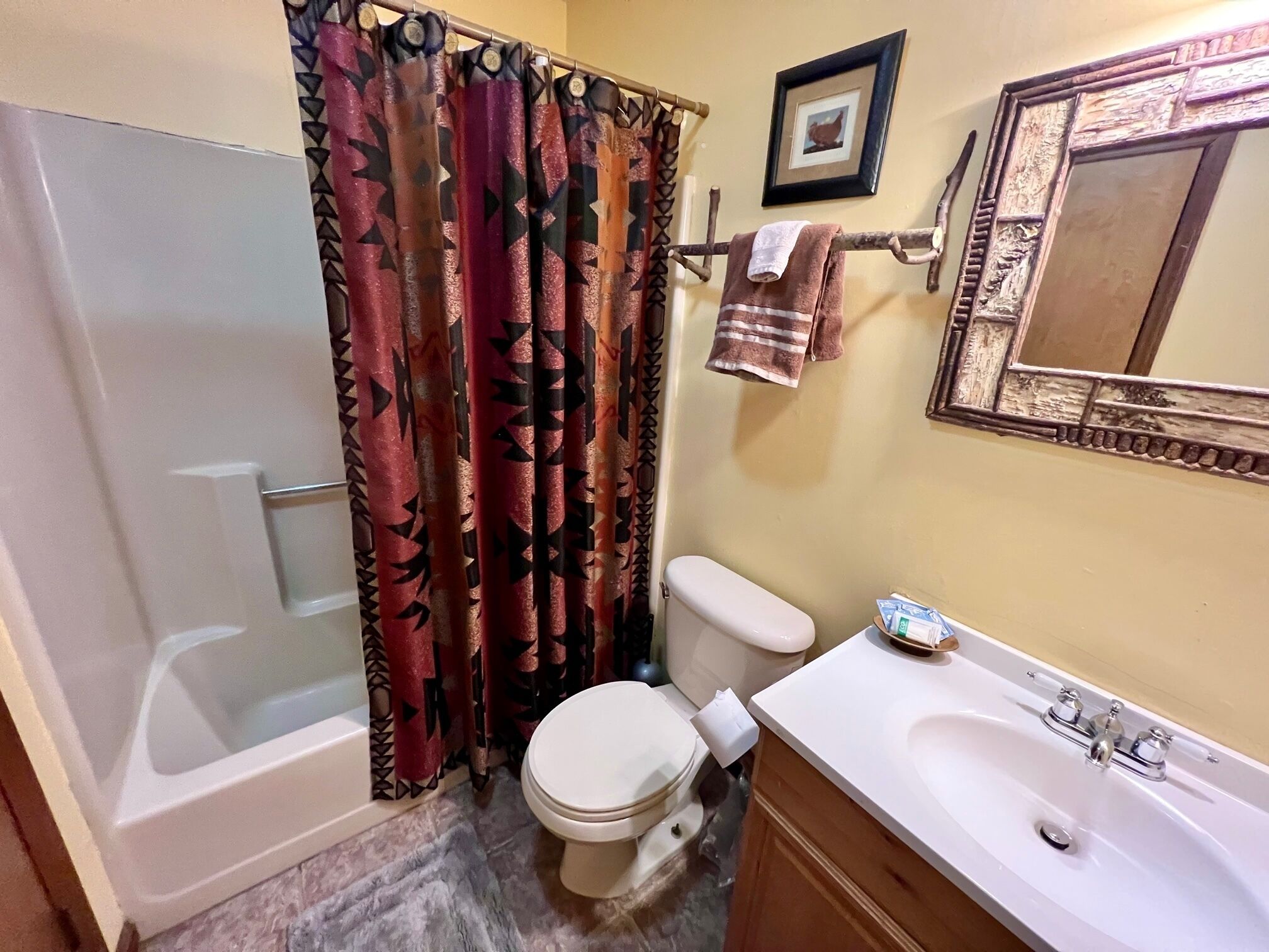 A bathroom with a bathtub, toilet, sink, and a shower curtain with a geometric pattern.