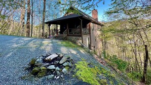 A rustic cabin with a porch, surrounded by trees and a gravel path leading to it. - August Place - Hot Tub, Community POOL, Game Table (Banner Elk)