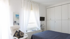A bedroom with a bed, a desk, a chair, a TV, and a wardrobe.