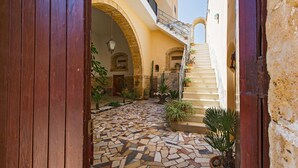 An interior courtyard with a tiled floor, stone arches, and potted plants.