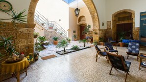 A spacious courtyard with a stone archway, potted plants, and outdoor seating.