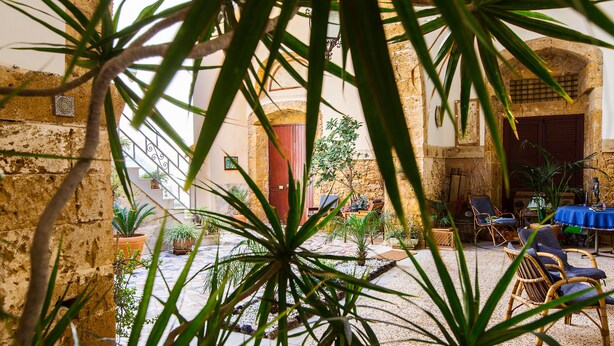 A courtyard with stone walls, potted plants, and outdoor seating.