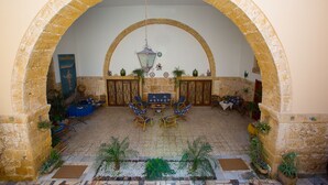 A courtyard with a stone archway, a hanging lantern, and a seating area with chairs and a table.
